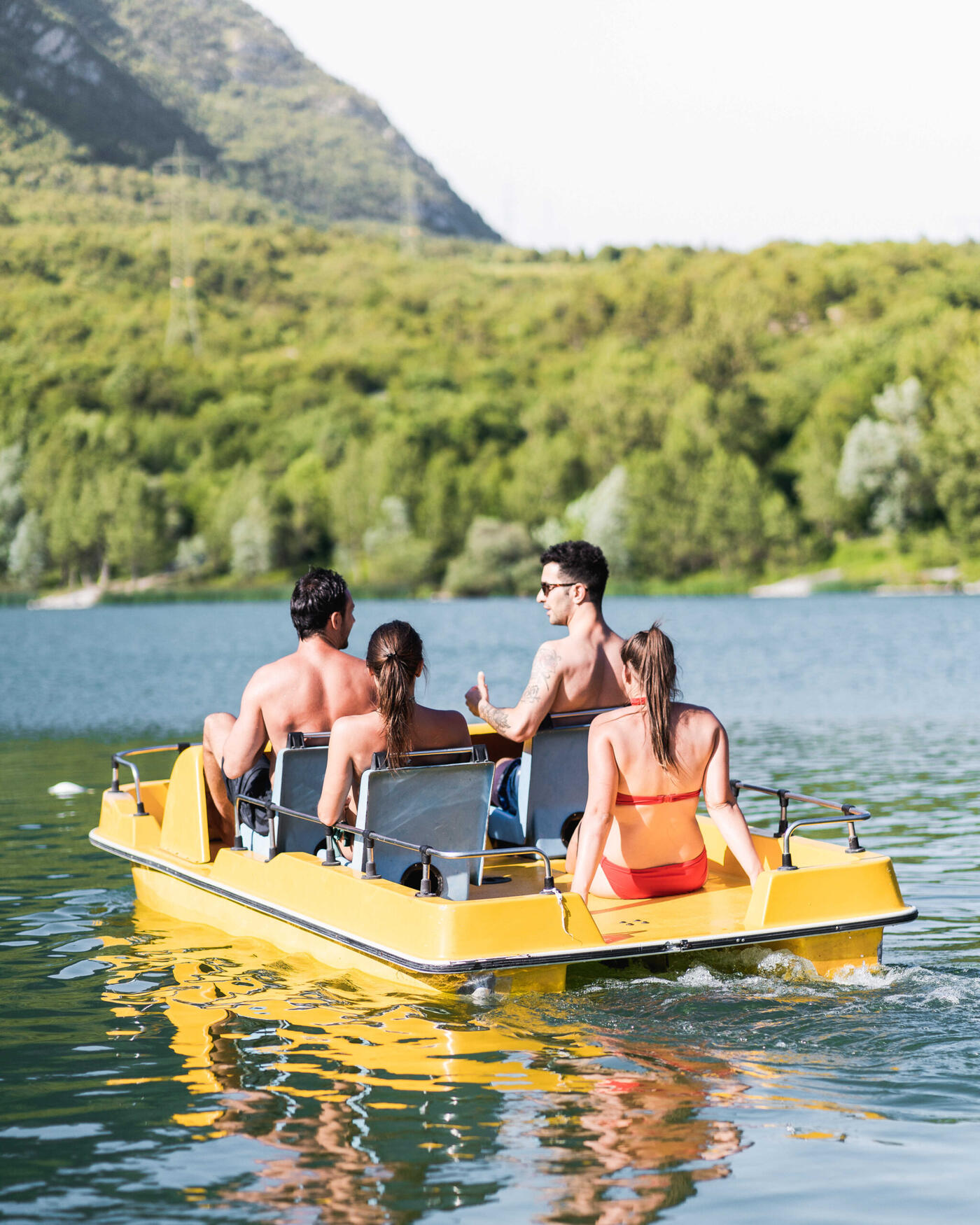 Quattro amici su un pedalò giallo in mezzo al lago